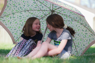 Sisters Together Beneath an Umbrella in Spring